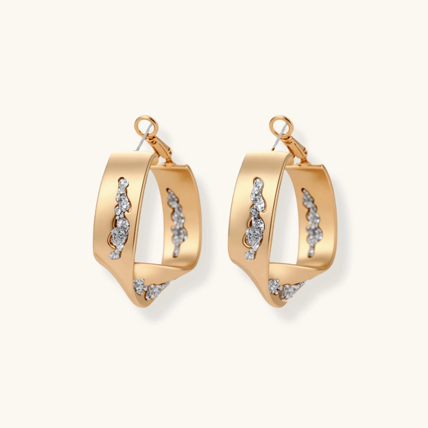 Sculptural wavy hoop earrings with crystal details and organic curved silhouette in gold and silver variants