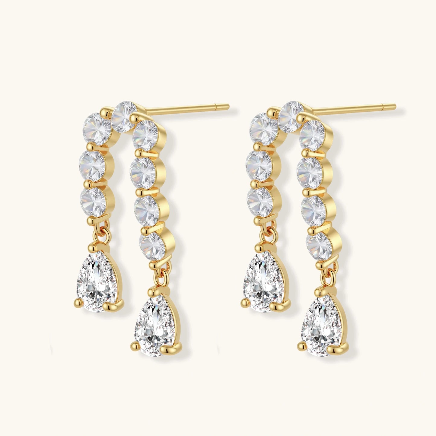 Gold-plated earrings with vertical line of clear crystals and teardrop pendants on neutral background