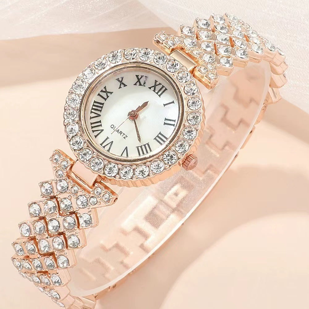 Rose gold watch with crystal embellishments on a light pink background