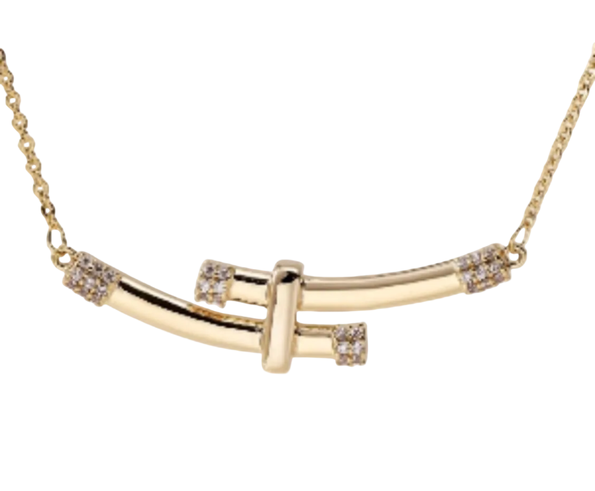 A gold bar necklace with a central T-shaped bar and small clear crystal accents on the ends, shown against a plain off-white background.