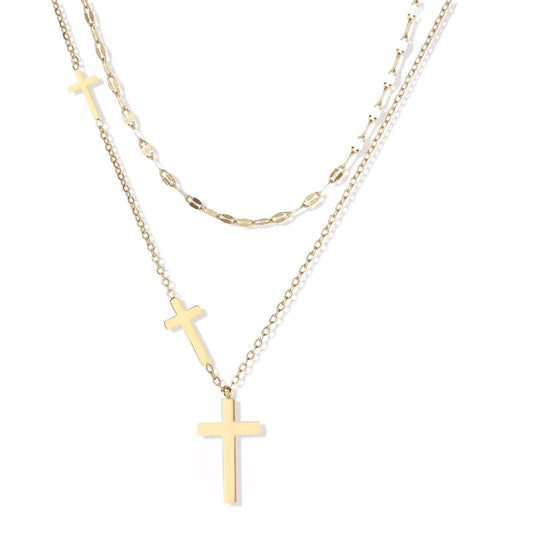 Three-layered gold necklace set with graduated cross pendants in mixed chain styles on white background.