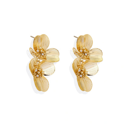 Pair of gold-plated double flower earrings with textured petals and crystal centers on cream background.