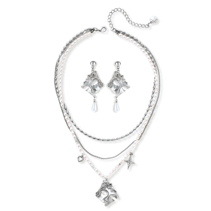 Ornate silver-toned masquerade mask jewelry set featuring rhinestone details and pearl drop earrings on white background.