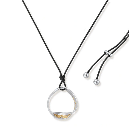 Artistic jewelry set featuring curved silver pendant with gold veining on black cord plus matching asymmetrical hoop earrings