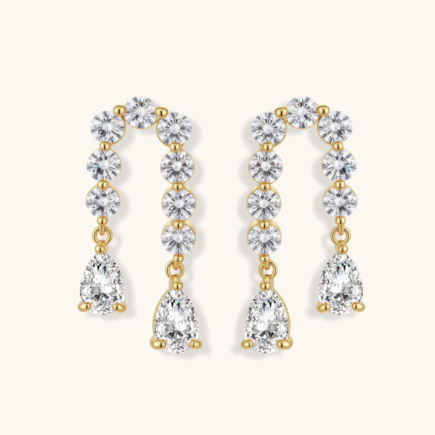 Gold-plated earrings with vertical line of clear crystals and teardrop pendants on neutral background