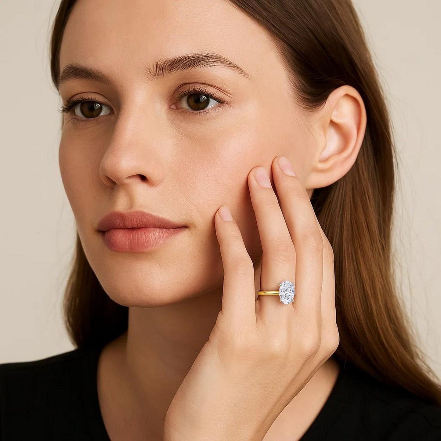 Woman wearing a gold ring with a diamond on a beige background