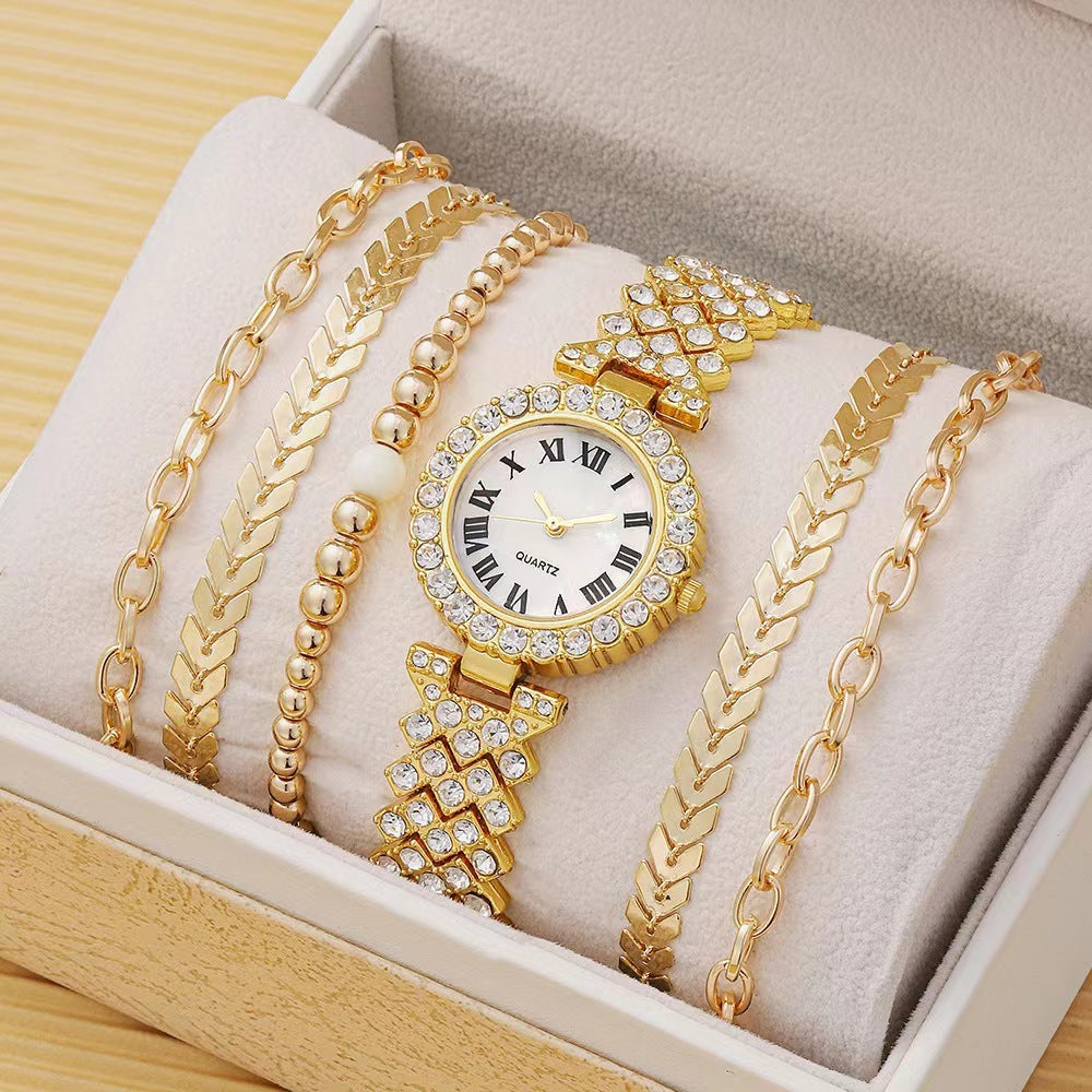 Gold watch and bracelets on a soft surface with a wooden box background