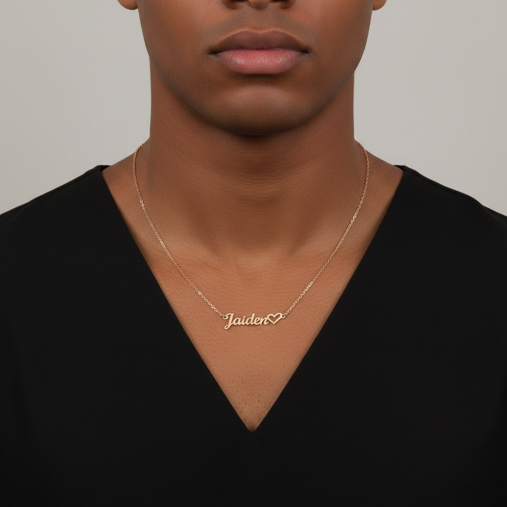 Young male wearing a silver necklace with a name pendant 'Jaiden' on a plain background
