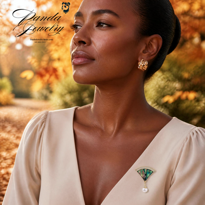 Woman wearing the Iridescent Fan Pearl Brooch on a fall dress top — Art Deco abalone shell fan pin with freshwater pearl drop and crystal accents in 14K gold-plated eco-brass